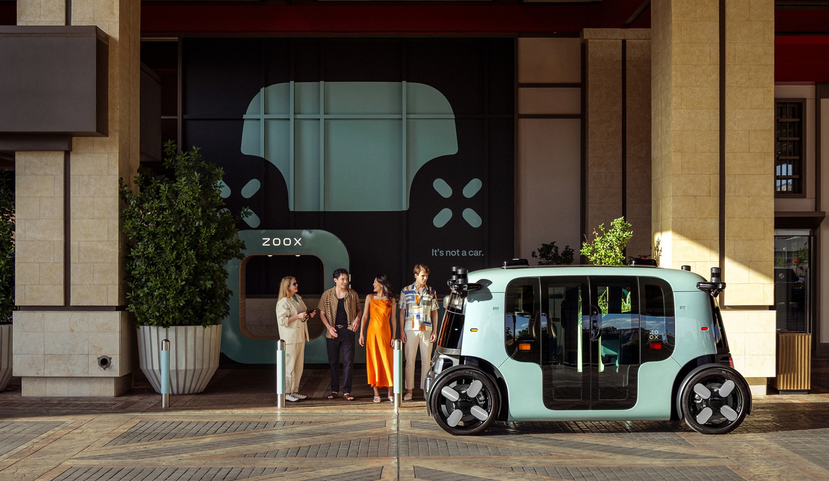 Four people waiting for a Zoox robotaxi at Resorts World Las Vegas