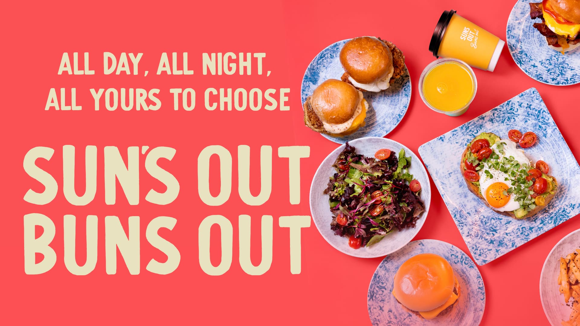 Plates of breakfast foods including sandwiches, toast with egg, salad, and fries arranged on blue patterned dishes next to coffee and juice cups on a coral-red background. Large text reads “Sun’s Out Buns Out – All Day, All Night, All Yours to Choose.”