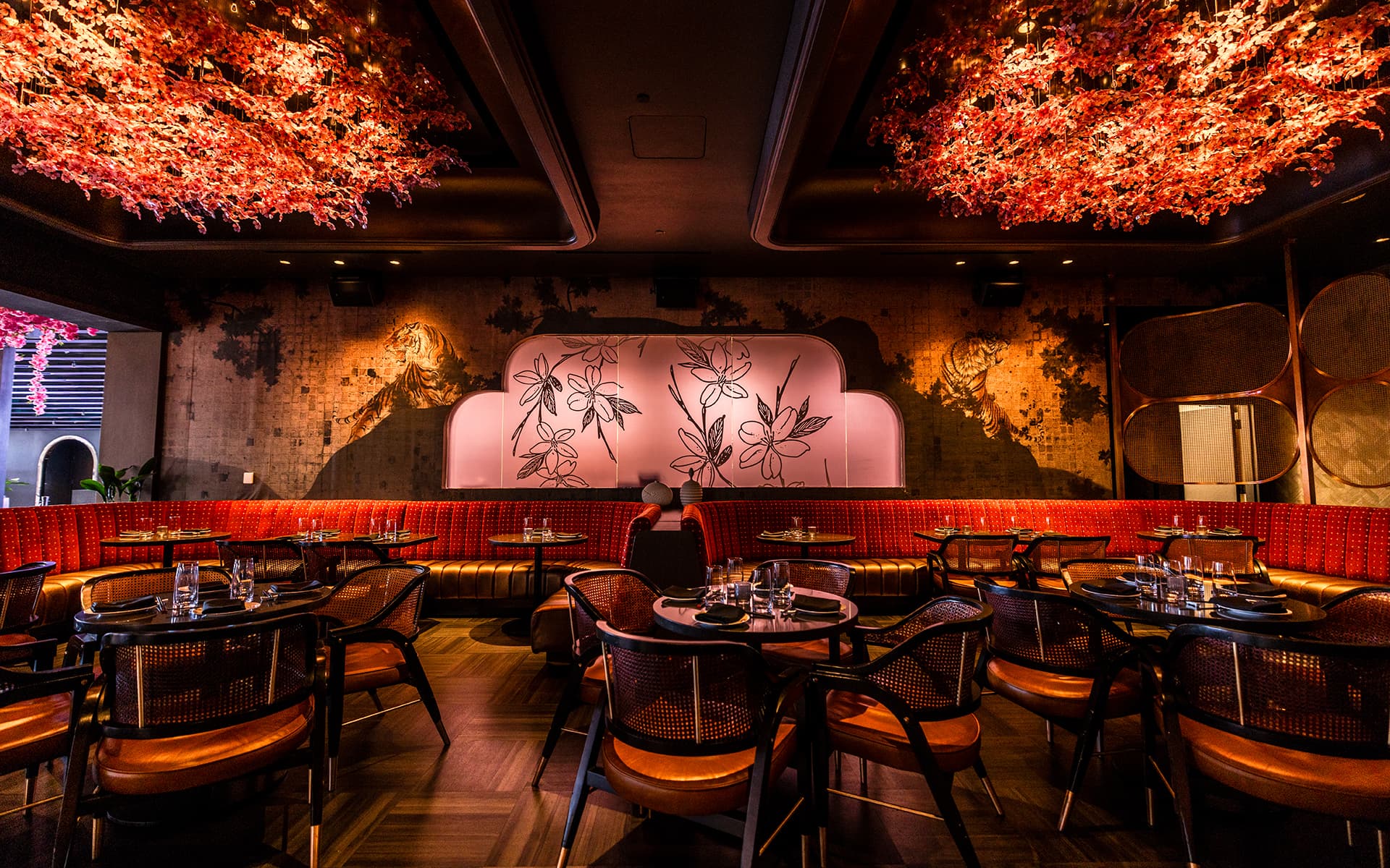 Elegant dining room at FUHU featuring red banquette seating, floral ceiling installations, warm ambient lighting, and contemporary Asian-inspired décor.