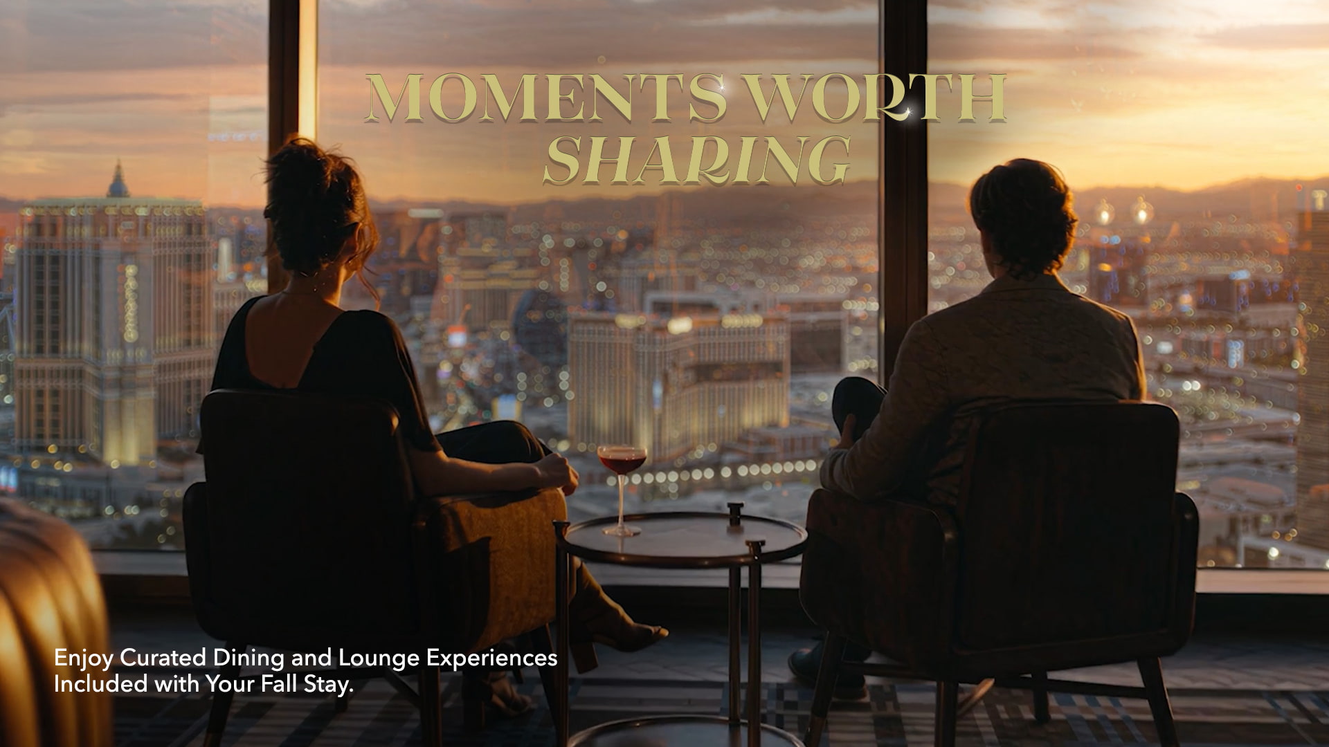 A couple in armchairs overlooks a sunset view of the Las Vegas strip skyline from a high-rise window. Text reads: "MOMENTS WORTH SHARING. Enjoy Curated Dining and Lounge Experiences Included with Your Fall Stay."