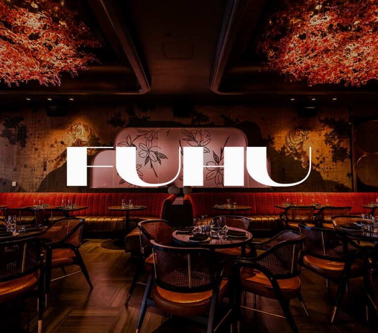 Banner featuring the interior of FUHU restaurant with modern dining tables, red banquette seating, floral ceiling décor, tiger wall murals, and the FUHU logo displayed prominently across the center.