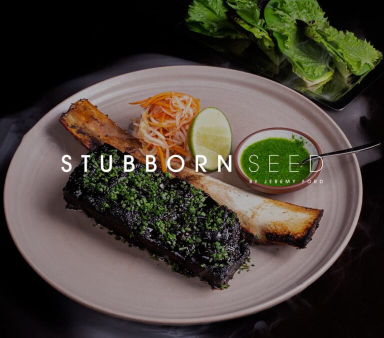 Banner featuring Stubborn Seed by Jeremy Ford with a plated roasted bone marrow dish served with herb sauce, pickled vegetables, lime, and leafy greens on a dark background.