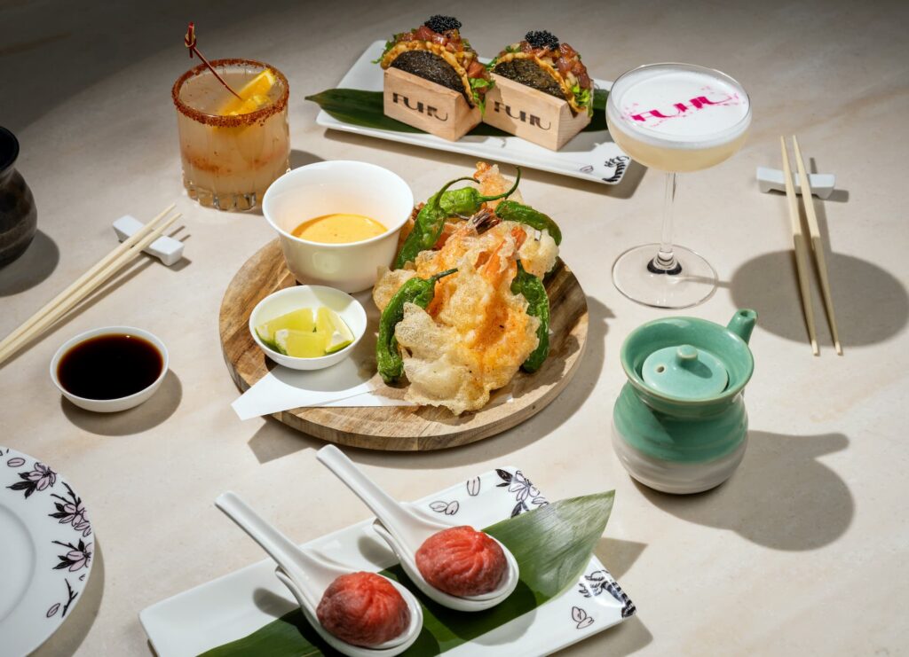 Assortment of shrimp chips, ahi poke tacos, and lobster soup dumplings served on a dining table.
