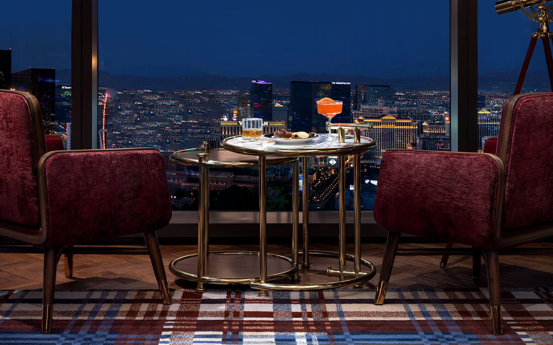 Lounge seating with cocktails and a panoramic nighttime view of the Las Vegas Strip.
