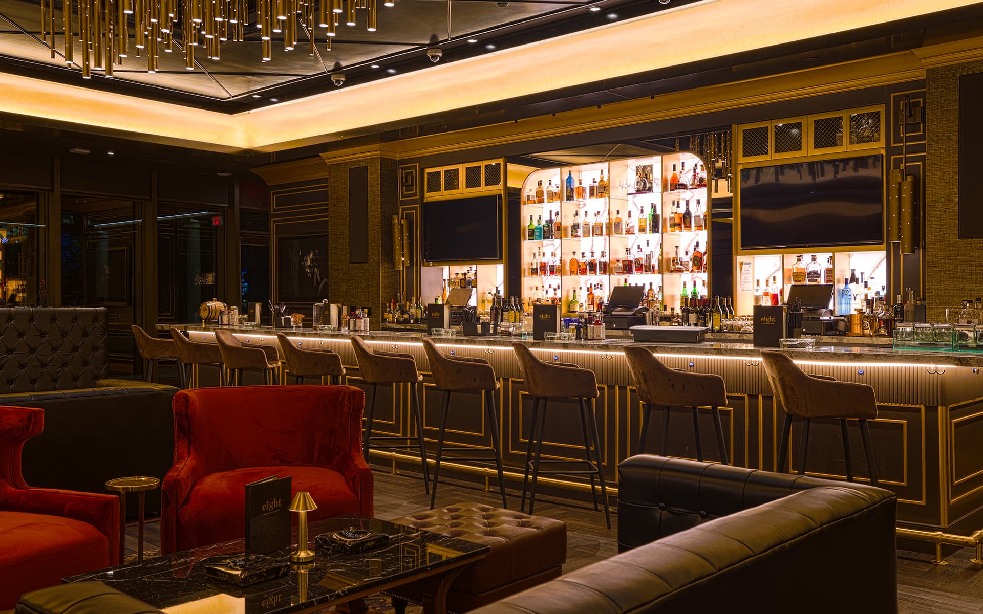Interior of Eight Lounge at Resorts World Las Vegas featuring an illuminated bar, lounge seating, and warm gold accents.