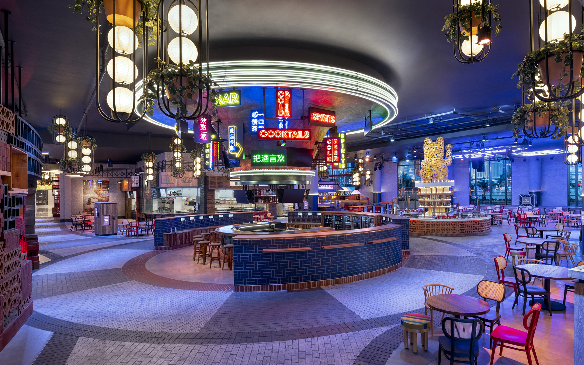 Interior of Famous Foods Street Eats at Resorts World Las Vegas, featuring a central bar, colorful neon signs, hanging lights, and dining areas.