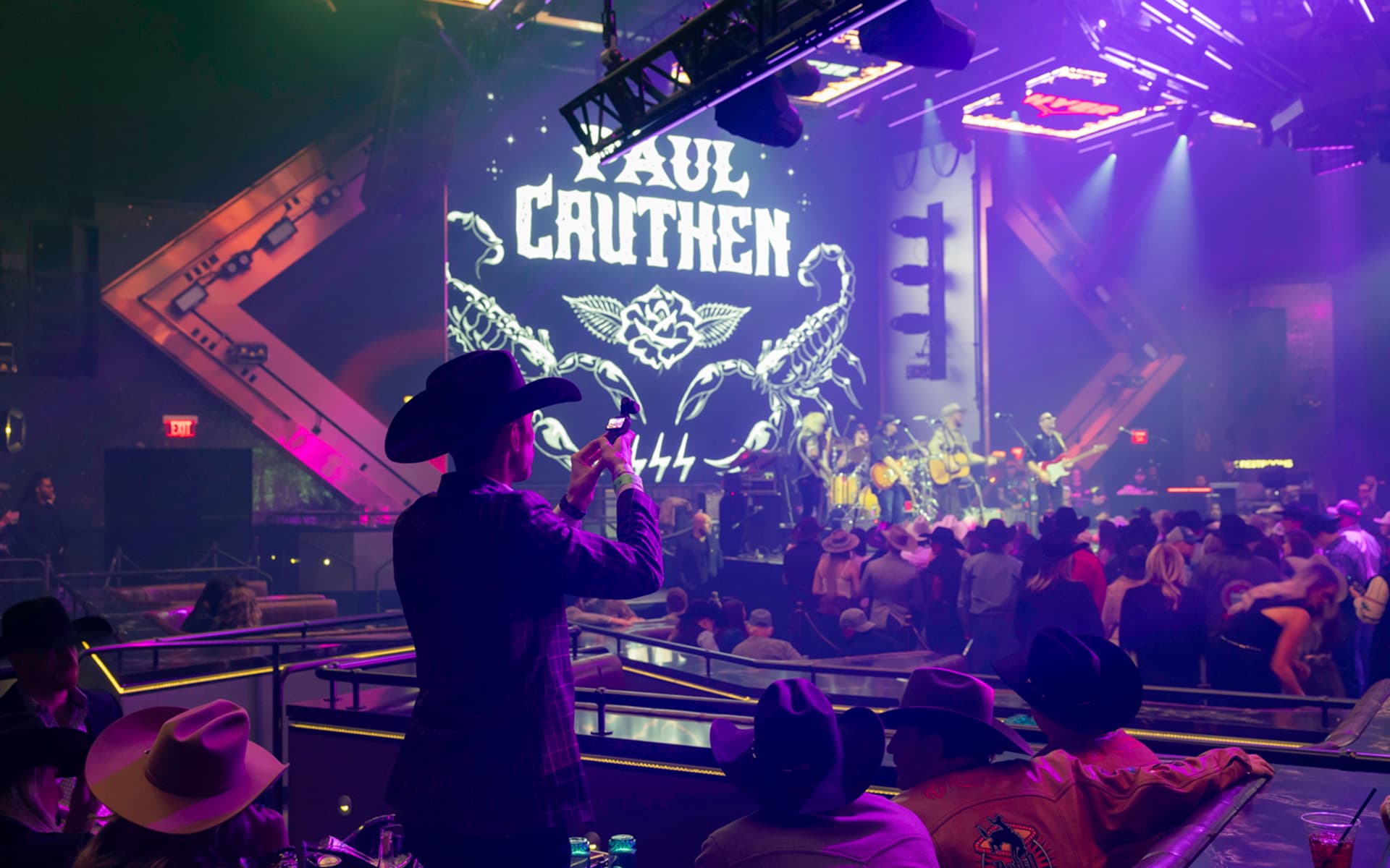 Crowd in cowboy hats watches a live band perform on stage under purple lighting at Zouk Nightclub.